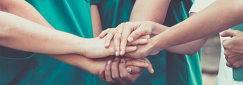 Group of nurses hands together in a solidarity circle.