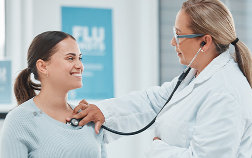 A medical professional listens to a woman's chest with a stethoscope