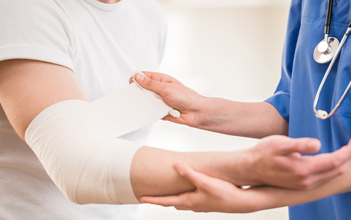 A man gets his elbow wrapped in a tension bandage by a medical professional.